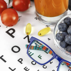 Tomatoes, glass of carrot juice, blueberries, eyeglasses on Snellen table